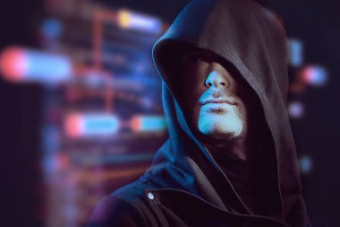 Dijital hologramların arka planında siyah başlıklı, kendine güvenen bir bakışla odaklanmış bir adamın portresi. Siber tema. Bitcoin, kripto para birimi. Boşluğu kopyala. 