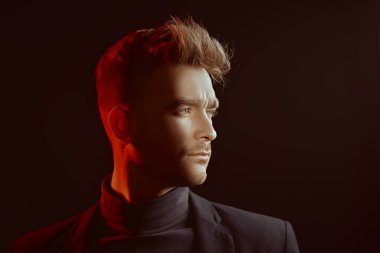 Yan tarafa bakan yakışıklı, vahşi bir adamın portresi. Karma ışık ve kopyalama alanı olan siyah bir stüdyo. Psikolojik sanat portresi.