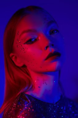 Güzellik konsepti, makyaj ve makyaj malzemeleri. Parlak makyajlı, neon mavisi kıpkırmızı bir kızın yakın plan portresi. Göz kamaştırıcı bir stil..