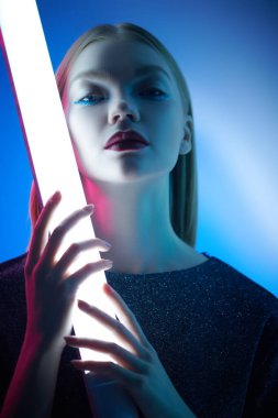 Göz kamaştırıcı parlak stil, sanatsal makyaj. Parlak makyajlı, neon lambaların ışığında sarı saçlı güzel bir manken kızı portresi. Stüdyo çekimi. Güzellik ve makyaj.. 