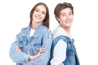 Beyaz arka planda poz veren şık kot elbiseli mutlu genç erkek ve genç kız portresi. Denim tarzı, gençlik tarzı..