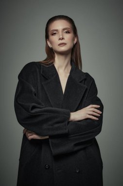 Modern tarz. Siyah keçeli ceket giyen kendine güvenen şık bir kadının portresi. Gri stüdyo geçmişi. Kadın modası.