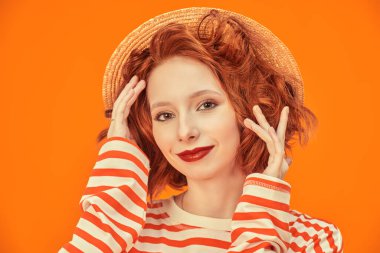 Yaz havası. Parlak kıvırcık saçlı neşeli bir kız kameraya gülümsüyor. Turuncu stüdyo geçmişi. Mutlu hayat resimleri.