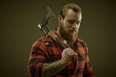 Ekose gömlekli, baltalı, vahşi sakallı bir adamın portresi. Koyu gri stüdyo geçmişi. Erkek güzelliği ve erkeklik. Berber dükkanı reklamı.