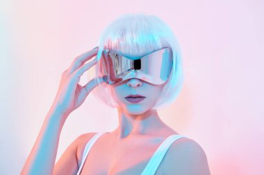 Fütürist kostümlü Polonyalı dansçı kız beyaz stüdyoda poz veriyor. Mavi ve pembe ışıkla. Siber punk kızı. Boşluğu kopyala. 