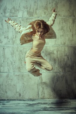 Modern stil dansçı kız grunge stüdyosunun arka planına atlıyor. Modern danslar.  