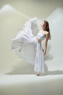 Narin beyaz elbiseli zarif bir balerin ifade ile dans eder. Modern balerin. Tam boy stüdyo resmi..