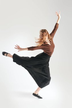 Stüdyoda gri arka planda poz veren genç dansçı kız. Tam boy portre. Modern dans stili. 