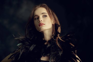 Dans sanatı. Siyah arka planda tüyleri olan siyah elbiseli güzel bir dansçı kızın portresi. Siyah Kuğu. Boşluğu kopyala.