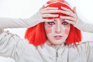 Parlak kırmızı makyajlı ve şık kızıl saçlı çekici bir bilimkurgu cyborg kızın yakın plan portresi. Siber punk konsepti. Makyaj ve saç stili. Beyaz arkaplan. 