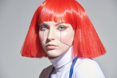 Makyaj ve saç stili. Açık arkaplanda parlak kırmızı makyajlı ve şık kızıl saçlı çekici bir bilimkurgu cyborg kızın yakın plan portresi. Siber punk kavramı.