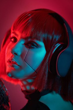 Parlak kırmızı makyajlı, şık kızıl saçlı, kulaklıklı, neon kırmızılı ve mavi ışıklı çekici bir kız. Gece partisi. Disko siber punk kızı. 