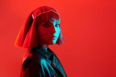 Çekici bir siber punk kızı kırmızı ışıkta kırmızı arka planda poz veriyor. Bilim kurgu cyborg kızı. Oyun, sanal gerçeklik. 