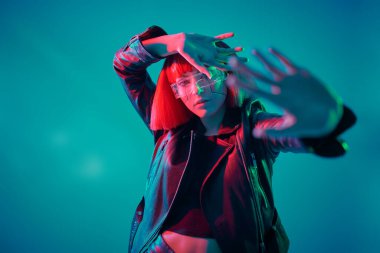 Bilim kurgu cyborg kızı. Çekici bir siber punk kızı karışık ışıkta mavi bir arka plana karşı poz veriyor. Oyun, sanal gerçeklik. 