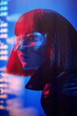 Parlak kırmızı makyajlı ve kızıl saçlı şık bir siber kızın portresi karışık neon ışıkta duruyor. Siber punk konsepti. Fütürist teknoloji tarzı. VR oyunları.