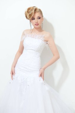 Avangard düğün stili ve moda. Parlak makyajlı, uzun beyaz elbiseli güzel bir gelin ve zarif bir saç stili. Stüdyo resmi.