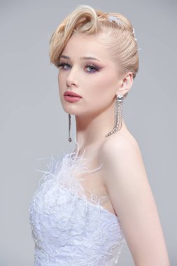 Avangard düğün modası. Parlak bir düğün makyajı ve şık bir saç stili olan, beyaz gelinlikli, abartılı sarışın bir kızın portresi. Stüdyo çekimi. Güzel gelin..