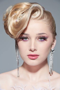 Avangard düğün modası. Parlak bir düğün makyajı ve zarif saç stili olan abartılı sarışın bir kızın portresi. Güzel gelin. Akşam makyajı ve saç stili. Stüdyo çekimi.