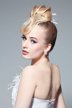 Avangard düğün modası. Parlak bir düğün makyajı ve şık bir saç stili olan, beyaz gelinlikli, abartılı sarışın bir kızın portresi. Güzel gelin. Stüdyo çekimi.