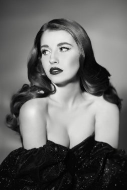 Hollywood dalgası saç stili ve şık akşam makyajlı, stüdyoda şık bir siyah gece elbisesi giymiş çekici esmer bir kadının siyah beyaz bir fotoğrafı. 30 'ların ve 40' ların Hollywood tarzı.