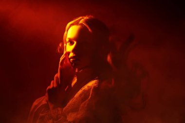 Peri sanatı fantezisi. Beyaz dantel elbiseli güzel bir kız, sıcak bir ışık demeti tarafından aydınlatılmış, donmuş. Uçan saçlar.