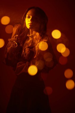 Sıcak altından bir ışıkla aydınlatılmış uzun beyaz dantelli güzel bir kızın portresi. Sanat fantezisi. Stüdyo görüntüsü koyu kırmızı arkaplan üzerine.