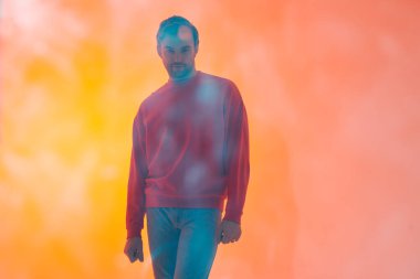 Yakışıklı, olgun bir adamın sanat portresi. Kamerayı dört gözle bekliyor. Portakal rengi ışık ve fotokopi alanı olan bir stüdyo portresi. Psikoloji, duygular.