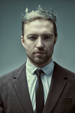 Başarı kavramı. Yakışıklı, bakımlı, iş elbisesi giymiş ve başında taçla sakin ve kendinden emin görünen olgun bir adamın portresi. İş ve başarılı yaşam tarzı. 