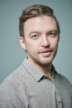 İnsanlar, duygular. Kameraya gülümseyen orta yaşlı bir adamın portresi. Erkek sağlığı ve güzelliği. Gri arkaplanda stüdyo portresi. 