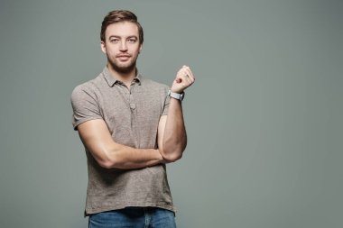 Kameraya gülümseyen gri tişörtlü orta yaşlı bir adamın portresi. Erkek sağlığı ve güzelliği. İnsanlar, duygular. Fotokopi alanı ile gri bir arkaplanda stüdyo resmi. 