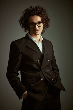 Erkek karakterler ve duygular. Koyu kıvırcık saçlı, küçük bıyıklı, klasik siyah takım elbiseli duygusal bir adam. Eski stilde bir stüdyo portresi.