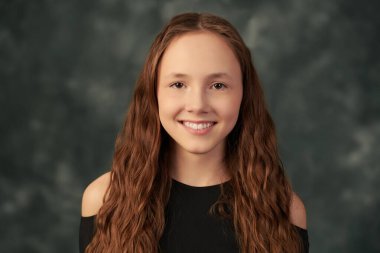 Güzellik ve gençlik modası. Uzun kahverengi saçlı ve kahverengi gözlü güzel bir genç kızın portresi grunge stüdyo arka planında. 