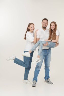 Mutlu, gülümseyen bir babanın iki sevgili kızıyla portresi. Mutlu aile kavramı. Beyaz arkaplanda stüdyo portresi.
