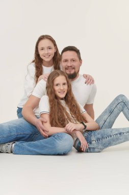 Mutlu, gülümseyen bir babanın iki sevgili kızıyla portresi. Beyaz arka planda stüdyo portresi. Mutlu aile kavramı.