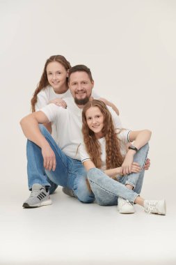 Sevdiği iki kızı olan mutlu, gülümseyen bir baba. Mutlu aile kavramı. Beyaz arkaplanda stüdyo portresi.