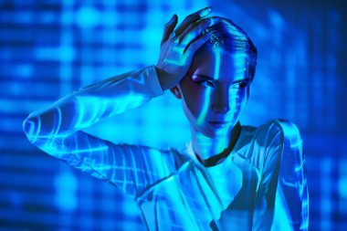 Geleceğin dijital teknolojileri. Fütürist tulumlu mükemmel siber kız dijital hologram ve neon ışınlarının ışığında duruyor. Siber uzay. VR oyunları.