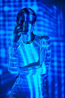 Geleceğin dijital teknolojileri. Fütürist tulumlu mükemmel siber kız dijital hologram ve neon ışınlarının ışığında duruyor. Siber uzay. VR oyunları.