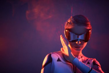 Fütürist gözlüklü güzel bir siber kızın portresi ateşin yansımalarının arka planında duruyor, kızgın ışınlar. Ozmik tarzda. Siber uzay.