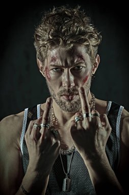 Yüzünde morluklar ve yaralar olan sert bir erkek haydut, karanlık bir odada duruyor ve agresif bir şekilde bakıyor. Kötü adam konsepti. Aksiyon filmi kahramanı.