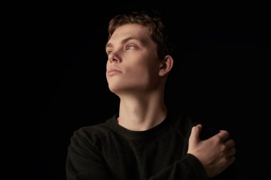 Siyah kazaklı yakışıklı ve düşünceli bir adamın portresi. Psikoloji, iç dünya. Kopyalama alanı olan siyah arkaplan.