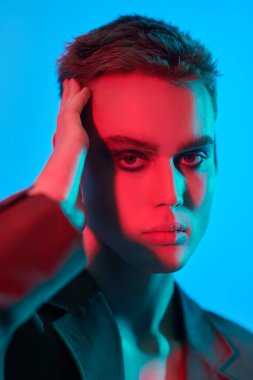 Stüdyoda karışık renkli neon ışıkta mavi arka planda poz veren şehvetli ve yakışıklı bir genç adamın sanat çekimi. Erkek güzeli. Sanat Moda Konsepti. 