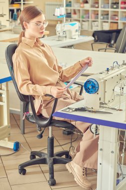 Giysi üretimi. Dikiş atölyesinde çalışan genç ve güzel bir kadının mesleği. Moda endüstrisi. 