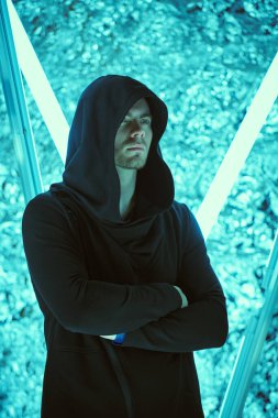 Fantezi kahramanı. Kafasında bir başlık olan siyah bir bornoz giymiş, neon lambaların ışığında duran cesur görünümlü yakışıklı bir adamın portresi. Uzay hakkında bilim kurgu. Sanal tema.