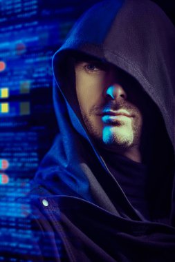 Dijital holograma karşı siyah başlıklı, kendine güvenen bir bakışla odaklanmış bir adamın portresi. Siber tema. Bitcoin, kripto para birimi. 