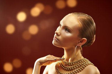 Altın lüks konsept. Altın tenli, makyajlı ve saçı altın sarısı takılar takan, parlak altın ışıklarla donatılmış muhteşem genç bir kadın. Noel güzeli kız. Boşluğu kopyala.