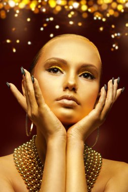Altın lüks stil. Altın tenli, makyajlı ve saçı altın sarısı takılar içinde altın yıldız tozuyla poz veren muhteşem bir kızın sanat portresi. Noel güzeli kız.. 