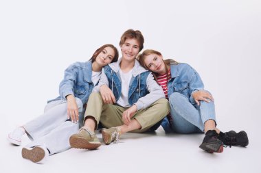 Denim tarzı, gençlik tarzı. Moda portresi beyaz bir stüdyo arka planında poz veren modaya uygun kot giymiş neşeli ve gülümseyen gençlerin.
