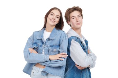 Beyaz arka planda poz veren şık kot elbiseli, gülümseyen genç kız ve erkek. Denim tarzı, gençlik tarzı..