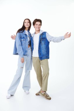 Beyaz bir arka planda poz veren duygusal genç bir erkek ve genç bir kızın moda çekimi. Gençlik duyguları. Gençler için Denim modası.
