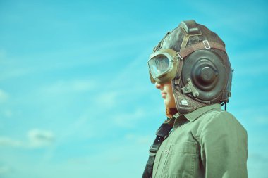 Çocukların rüyaları. Havacı kasklı ve gözlüklü bir çocuğun portresi mesafeye dik dik bakıyor. Mavi gökyüzü arka planı. Boşluğu kopyala.